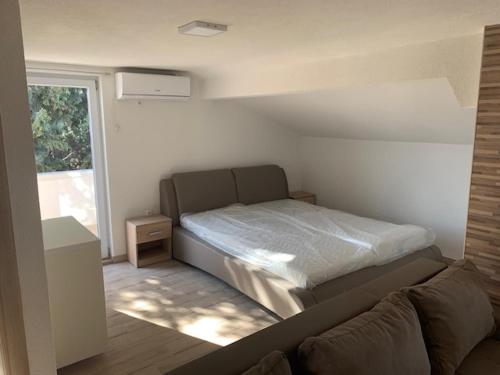 a bedroom with a bed and a couch and a window at Apartmani Dobra Villa in Vodice