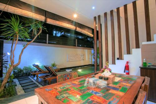 a dining room with a table and a palm tree at Villa Raka Managed by Manara in Legian