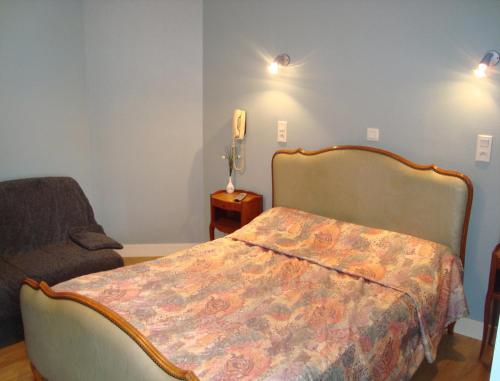 ein Schlafzimmer mit einem Bett, einem Stuhl und einem Telefon in der Unterkunft Splendid Hôtel in Montreuil-Bellay