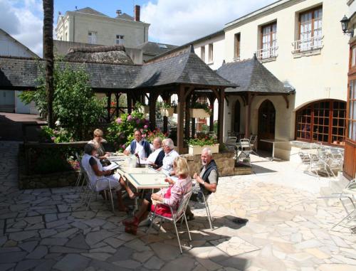 un groupe de personnes assises à une table dans un patio dans l'établissement Splendid Hôtel, à Montreuil-Bellay