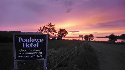 a sign for a hotel on a road with a sunset at Poolewe Hotel in Poolewe