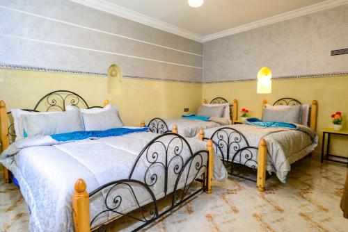Un dormitorio con dos camas con sábanas azules y blancas. en Hôtel Faouzi, en Marrakech