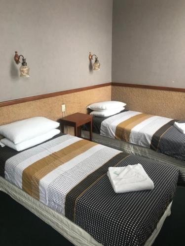 Grand Hotel - Whangarei في وانغاري: سريرين في غرفة الفندق عليها مناشف