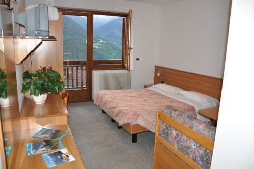 a bedroom with a bed and a desk and a window at Albergo Dolomiti in Capriana