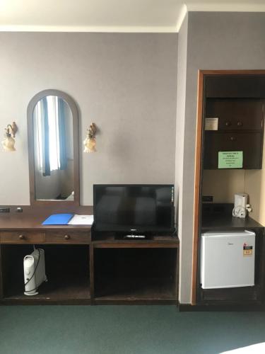 a room with a desk with a television and a mirror at Grand Hotel - Whangarei in Whangarei