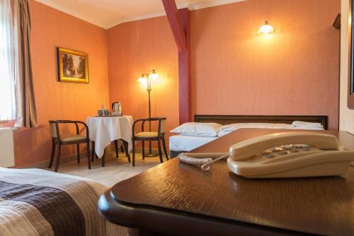 um quarto de hotel com duas camas e uma mesa com um telefone em Willa Koba em Ustroń
