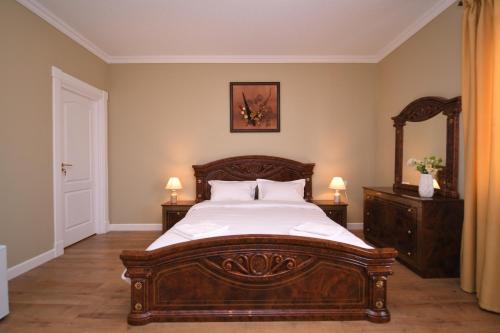 a bedroom with a large wooden bed and a mirror at Absolut Residence Hateg in Haţeg