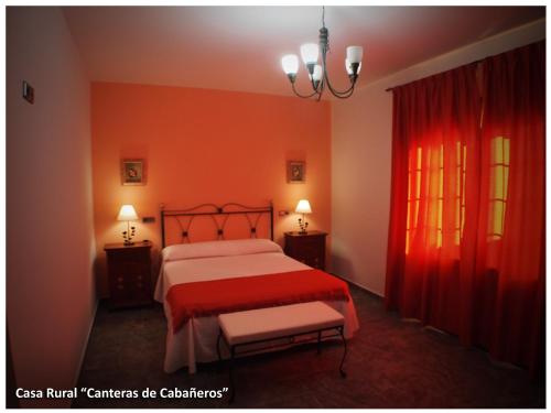 a bedroom with a red bed and a red curtain at Casa Rural Las Canteras de Cabañeros in Retuerta de Bullaque