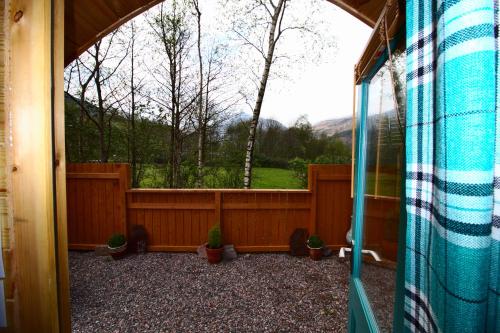 a view of a garden from the inside of a house at Nevis Pod, West Highland Way Holidays in Kinlochleven