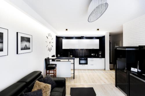 a living room with a black couch and a kitchen at Luxury Apartments in Kielce