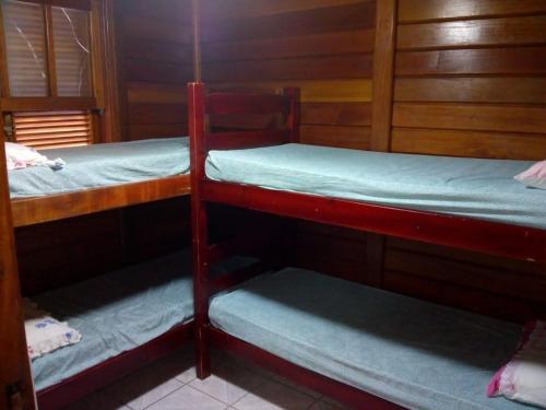 イーリャ・コンプリーダにあるIlha Comprida-Casa Madeira-Conforto Familiarの木製の壁の客室で、二段ベッド2組が備わります。