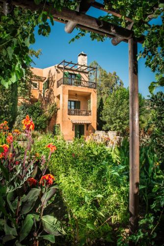 a building in the middle of a garden with flowers at Enagron Ecotourism Village in Axós