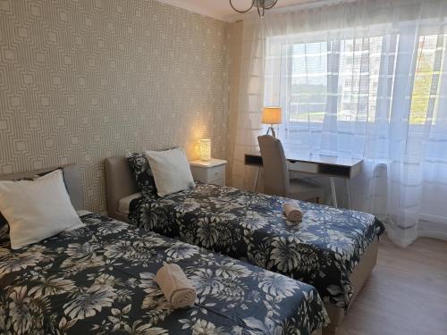 a bedroom with two beds and a desk and a window at Ventspils Seaside Lux Apartments in Ventspils