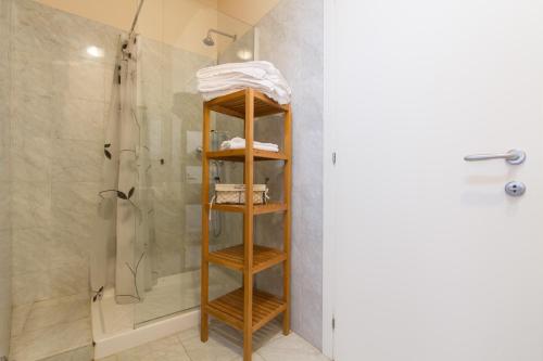 a bathroom with a shower and a wooden shelf at Casa Vacanza Fontana Del Delfino in Bergamo
