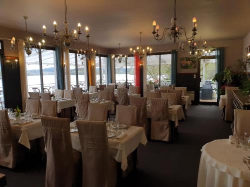 un comedor con mesas y sillas blancas y lámparas de araña en Hotel Restaurant La Caravelle, en Peyrat-le-Château