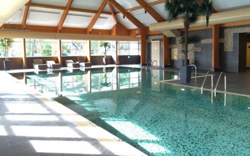 a large swimming pool in a building with chairs at Jeneverbes24 in Otterlo