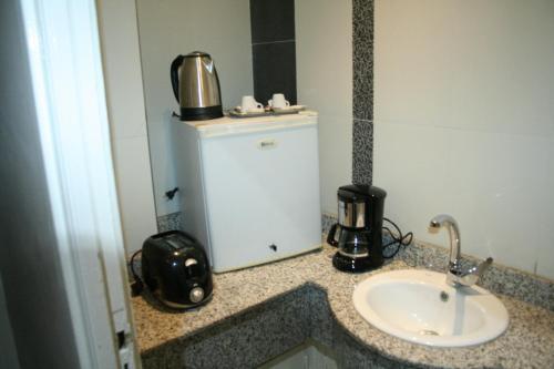 baño con lavabo y nevera pequeña en Ambassy Hotel en Kenitra