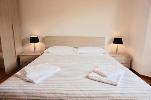 een groot wit bed met twee witte handdoeken erop bij appartamento benaco in Riva del Garda
