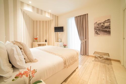 une chambre avec un grand lit blanc et une fenêtre dans l'établissement Rooms Milano Duomo, à Milan