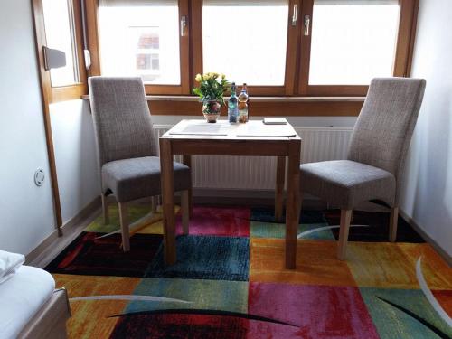 a dining room table with two chairs and a colorful rug at Ferienwohnung "Elsnerstrasse" in Nürnberg