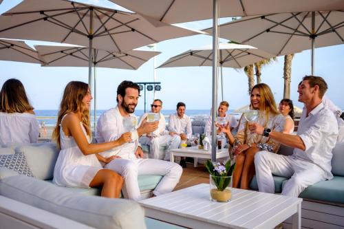 a wedding party sitting under umbrellas on the beach at Aldiana Club Costa del Sol in Alcaidesa