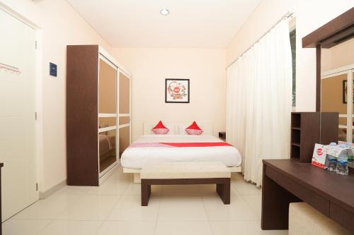 a bedroom with a bed and a bench in it at SUPER OYO 782 Menjangan Residence at Citraland 1 in Lontar