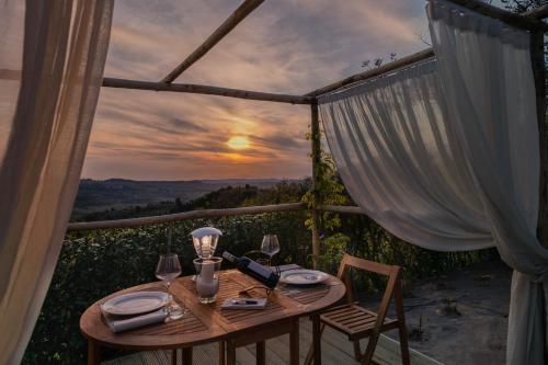 a table with wine glasses on a balcony with a sunset at Villa I Barronci Resort & Spa in San Casciano in Val di Pesa