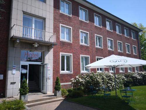 a building with a table and an umbrella in front of it at Hotel Haus vom Guten Hirten in Münster