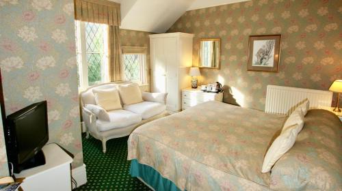 a bedroom with a bed and a chair and a television at Rylstone Manor in Shanklin