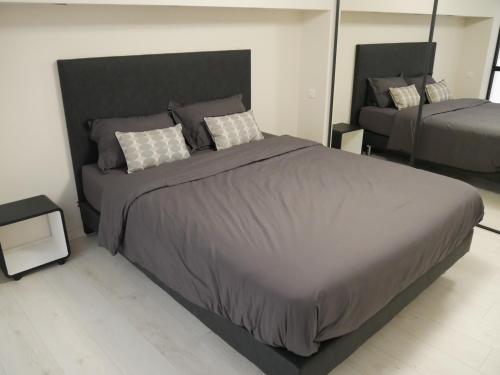 ein Schlafzimmer mit einem großen Bett mit einer grauen Bettdecke in der Unterkunft GRAND LOFT chic et moderne, déco industrielle in Beausoleil