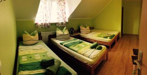 three beds in a room with green walls at Agroturystyka Nad Stawem in Centawa