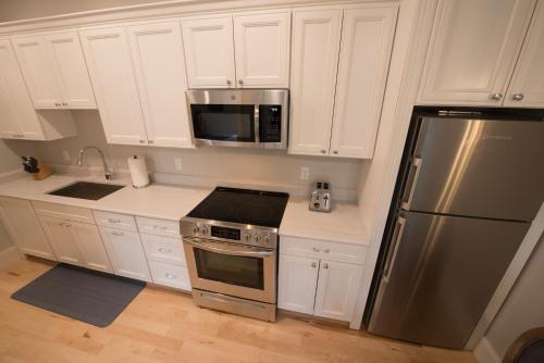 a kitchen with white cabinets and a stainless steel refrigerator at The Outlook Inn in Newport