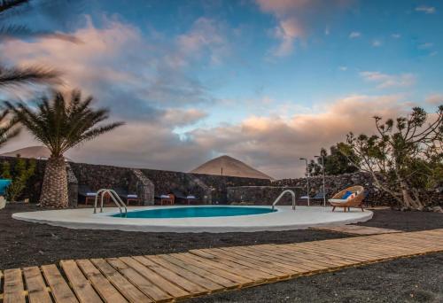 a pool with a palm tree and a pyramid in the background at Los Lirios Hotel Rural - Adults Only in Tías