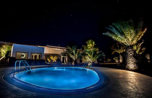 a swimming pool at night with palm trees and a house at Los Lirios Hotel Rural - Adults Only in Tías
