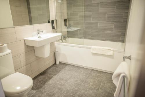 a bathroom with a sink and a tub and a toilet at Milton Manchester Hotel in Manchester