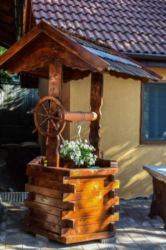 a wooden wishing well with a waterwheel in front of a house at Pensiunea Bogas in Praid