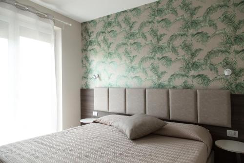 a bedroom with a bed with a tropical wallpaper at Menta e Rosmarino Rooms in Lazise