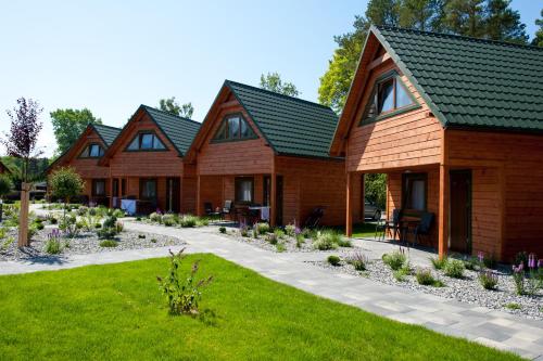 een rij houten huisjes met een groen dak bij Zem-Tourist in Pustkowo