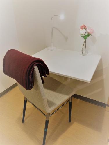 a white desk with a chair and a vase of flowers at Hällefors Vandrarhem-Hostel & Kanotcenter in Hällefors