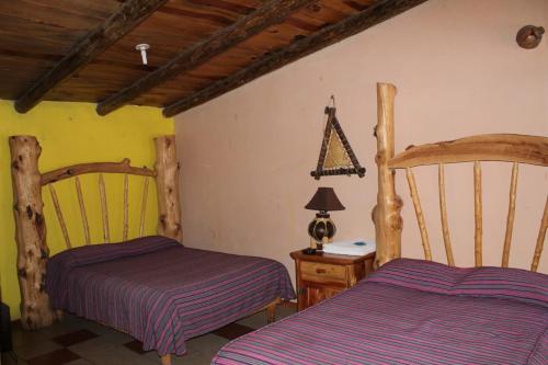 a bedroom with two beds and a table with a lamp at Cabañas Margarito in Areponapuchi