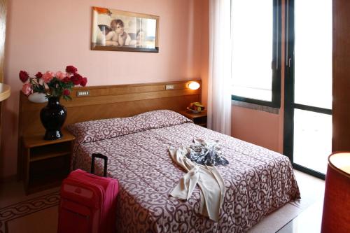 a hotel room with a bed and a suitcase at Hotel Dante Family Spa Resort in Cervia