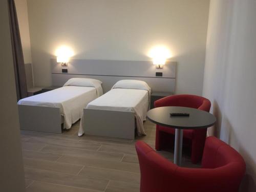 a room with two beds and a table and chairs at ROMA ROOMS in Ancona