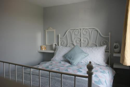 a bedroom with a bed with a gray headboard and pillows at Wayside Cottage in Saint Osyth