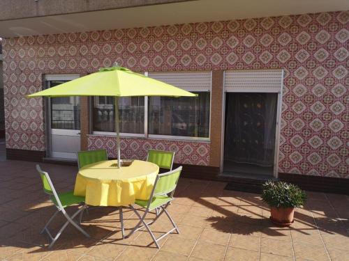 una mesa con una sombrilla amarilla frente a un edificio en Prothea Home en Vila Chã