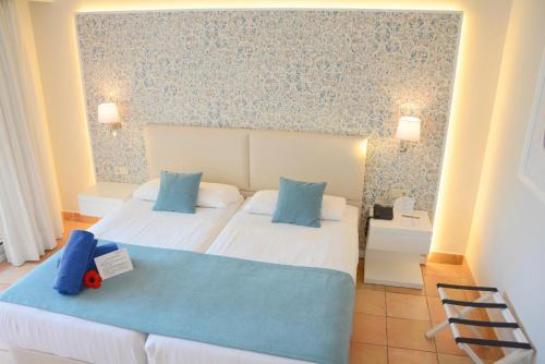 a hotel room with two beds with blue pillows at Aldiana Club Andalusien in Chiclana de la Frontera