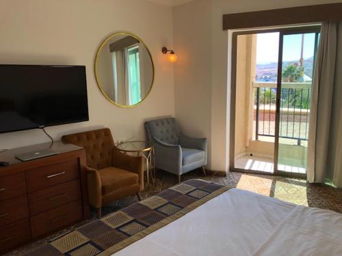a bedroom with a bed and a television and a chair at level of 5 star on the beach in Eilat
