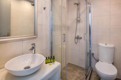 a bathroom with a sink and a shower with a toilet at Olive Tree Suites in Fira