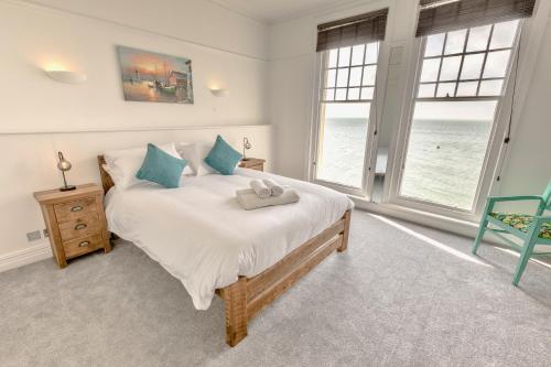 a bedroom with a bed and two windows at Pier View Apartment in Totland