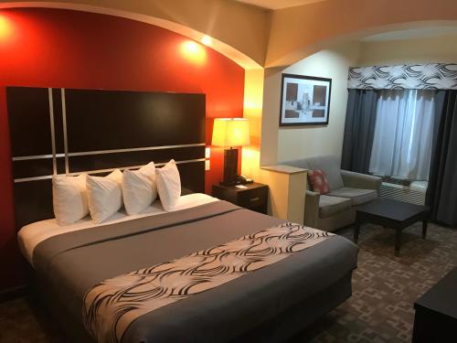a hotel room with a bed and a chair at Regency Inn & Suites - Baytown in Baytown