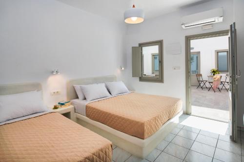 a bedroom with two beds and a mirror at Olive Tree Suites in Fira